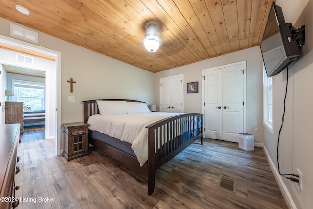 bedroom featuring multiple closets, wood ceiling, visible vents, and wood finished floors