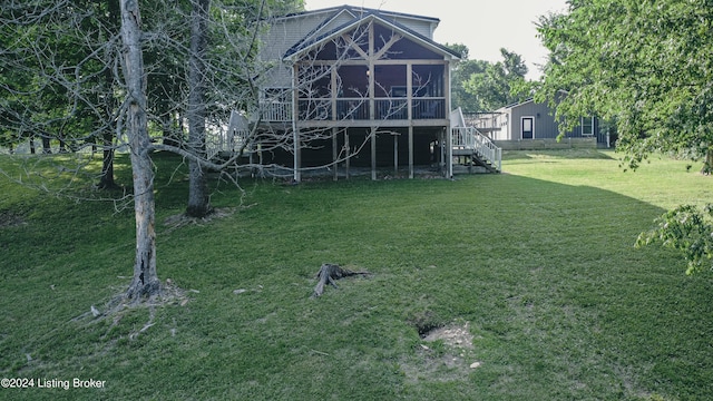 rear view of house featuring a sunroom, a yard, and stairway