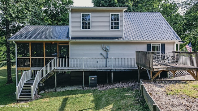 rear view of property featuring a lawn, a sunroom, metal roof, stairs, and a wooden deck