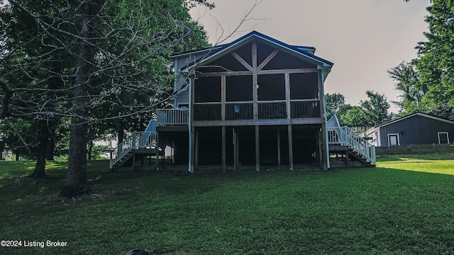 back of house with a sunroom, a lawn, and stairway