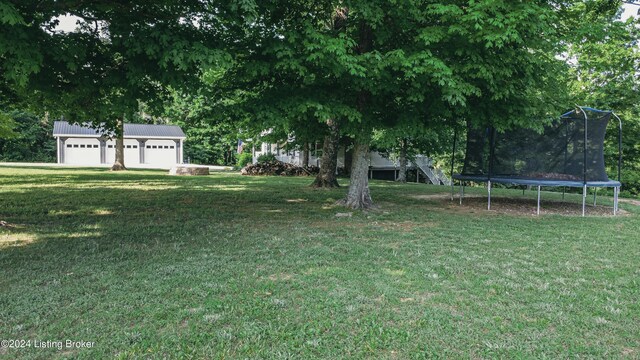 view of yard with a garage, a trampoline, and an outdoor structure