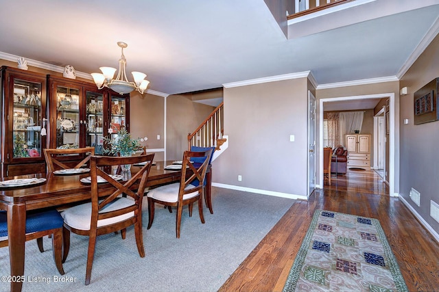 dining area with a notable chandelier, wood finished floors, baseboards, ornamental molding, and stairway