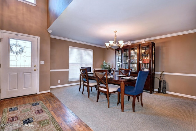 dining room with an inviting chandelier, baseboards, ornamental molding, and wood finished floors