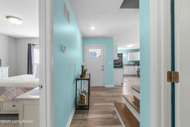 entryway featuring visible vents, baseboards, and wood finished floors