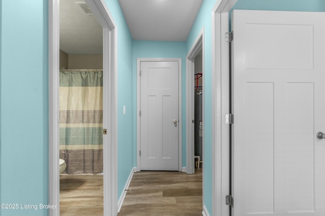 hallway featuring baseboards and wood finished floors