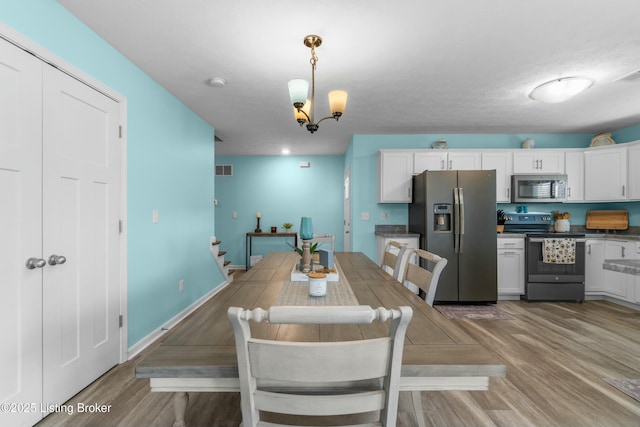 dining room featuring light wood finished floors, visible vents, baseboards, stairway, and a chandelier