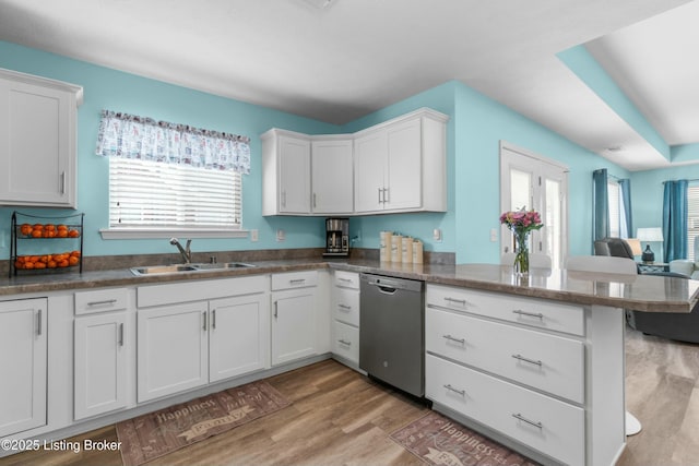 kitchen with light wood-style flooring, a peninsula, a sink, white cabinetry, and dishwasher