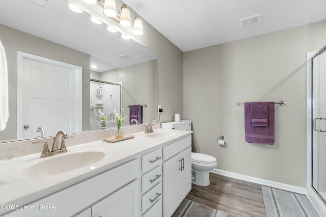 bathroom with a stall shower, visible vents, a sink, and wood finished floors