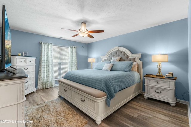 bedroom featuring a textured ceiling, ceiling fan, wood finished floors, and baseboards