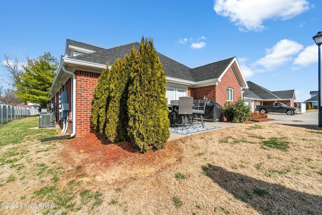 view of home's exterior with a patio, fence, a yard, central air condition unit, and brick siding