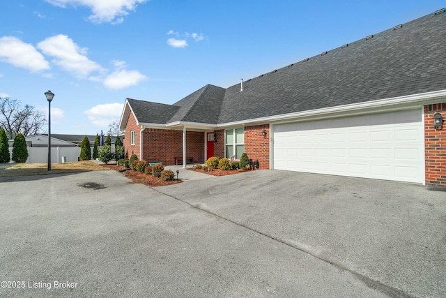 view of front facade featuring a garage, brick siding, driveway, and roof with shingles