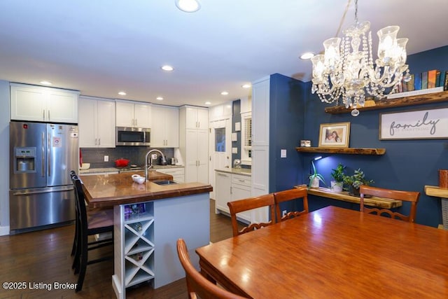 kitchen featuring butcher block countertops, a sink, white cabinets, appliances with stainless steel finishes, and tasteful backsplash