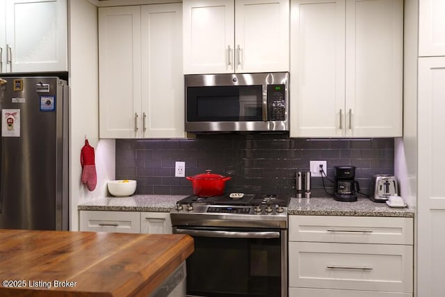 kitchen with white cabinets, appliances with stainless steel finishes, and wooden counters