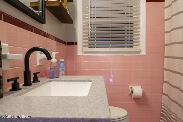 full bath featuring a sink, a shower with shower curtain, toilet, and tile walls