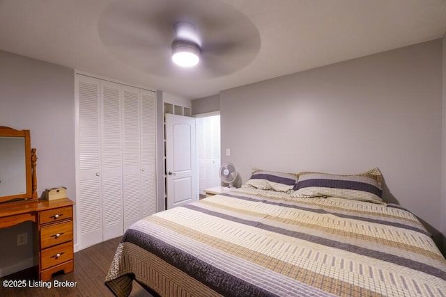 bedroom with a closet, dark wood-type flooring, and a ceiling fan