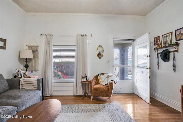 sitting room with baseboards, a textured ceiling, ornamental molding, and wood finished floors