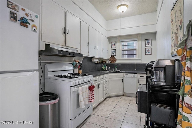 kitchen featuring dark countertops, white appliances, under cabinet range hood, and white cabinetry