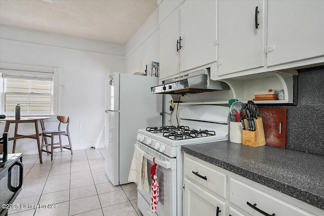 kitchen featuring light tile patterned flooring, under cabinet range hood, white appliances, white cabinets, and dark countertops