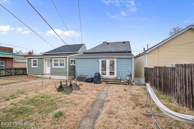 back of house with entry steps, a fenced backyard, roof with shingles, and french doors