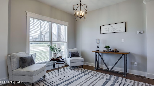 living area featuring an inviting chandelier, baseboards, visible vents, and wood finished floors