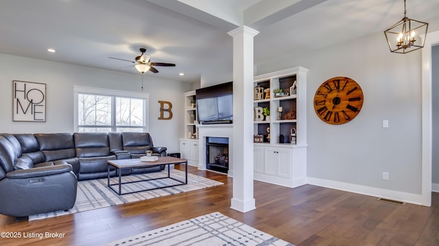 living area featuring decorative columns, baseboards, dark wood-type flooring, a fireplace, and recessed lighting