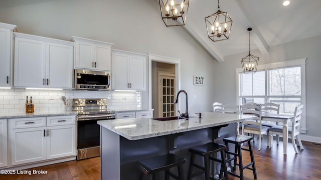 kitchen with a sink, white cabinetry, appliances with stainless steel finishes, decorative backsplash, and beamed ceiling