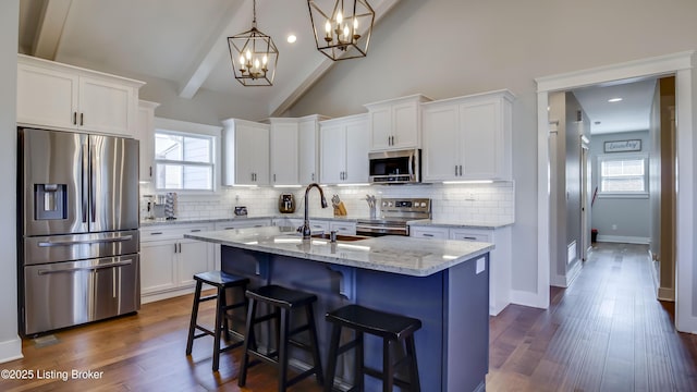 kitchen with beam ceiling, stainless steel appliances, white cabinetry, a sink, and a healthy amount of sunlight