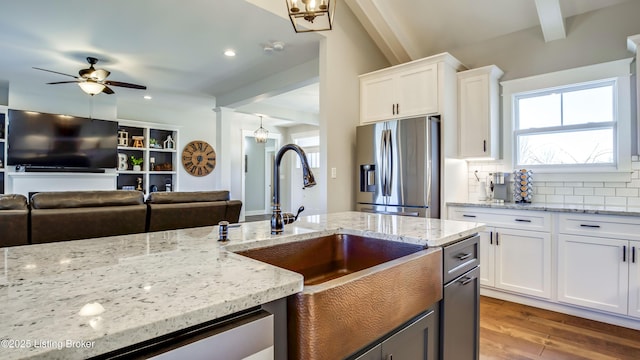 kitchen featuring stainless steel fridge, tasteful backsplash, wood finished floors, white cabinetry, and a sink