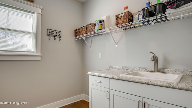 laundry room featuring baseboards, dark wood finished floors, and a sink