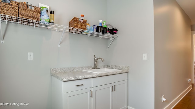 washroom with baseboards, a sink, and wood finished floors