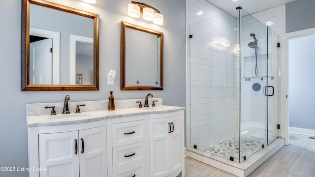 full bath with double vanity, a shower stall, and a sink