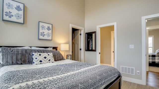 bedroom featuring a towering ceiling, carpet floors, baseboards, and visible vents