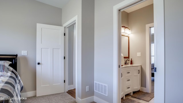 bedroom with baseboards, visible vents, and ensuite bathroom