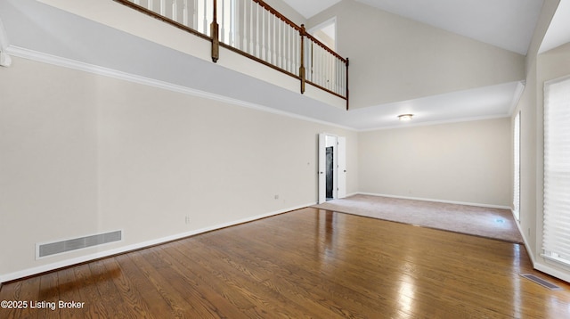 empty room featuring high vaulted ceiling, visible vents, and hardwood / wood-style floors