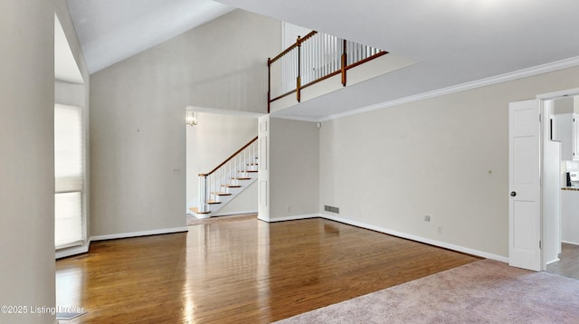 unfurnished living room with high vaulted ceiling, wood finished floors, visible vents, stairs, and ornamental molding