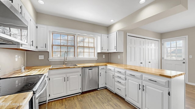 kitchen with light wood finished floors, a peninsula, stainless steel appliances, wooden counters, and a sink