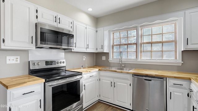 kitchen featuring a wealth of natural light, butcher block counters, stainless steel appliances, and a sink