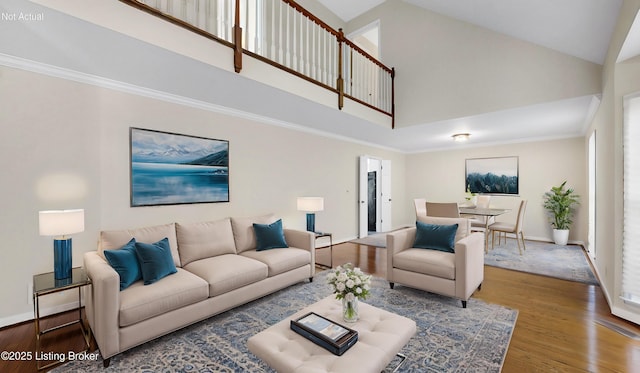 living room featuring baseboards, high vaulted ceiling, wood finished floors, and crown molding