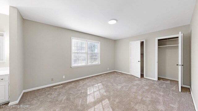 unfurnished bedroom with multiple closets, carpet flooring, and baseboards