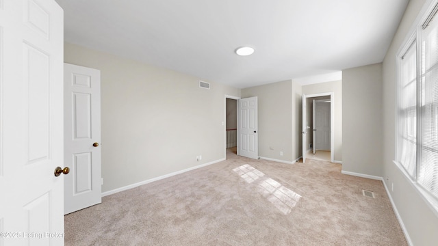 unfurnished bedroom with baseboards, visible vents, and light colored carpet