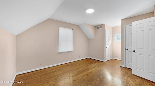 additional living space with visible vents, vaulted ceiling, baseboards, and wood finished floors