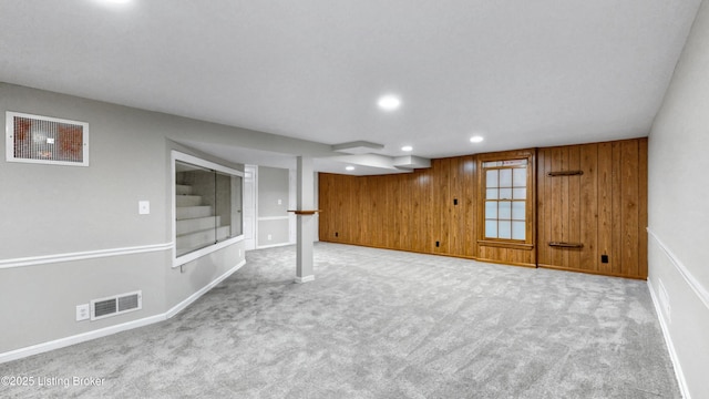 finished below grade area with carpet floors, recessed lighting, visible vents, and wood walls