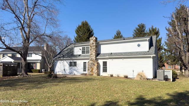 rear view of property featuring a shingled roof, central AC unit, a lawn, a chimney, and fence