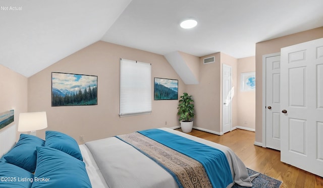 bedroom with visible vents, vaulted ceiling, baseboards, and wood finished floors