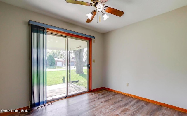 empty room with a ceiling fan, wood finished floors, visible vents, and baseboards