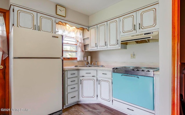 kitchen with range with gas cooktop, light countertops, freestanding refrigerator, a sink, and under cabinet range hood