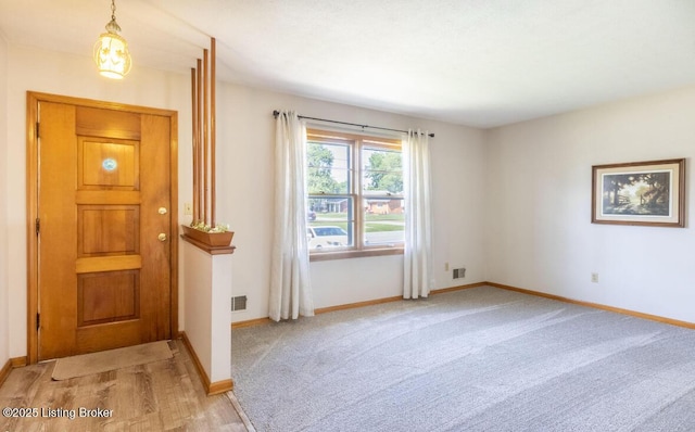 doorway with baseboards, visible vents, and light colored carpet