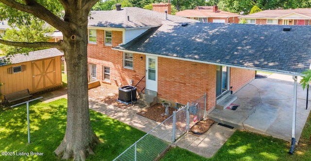 back of house featuring entry steps, brick siding, an outdoor structure, and roof with shingles