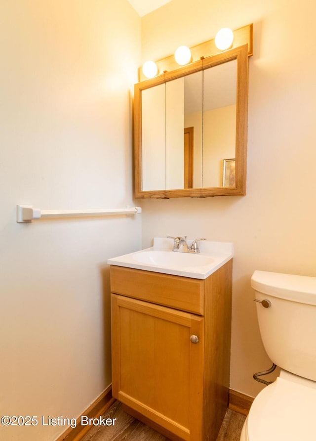 bathroom featuring toilet, wood finished floors, vanity, and baseboards