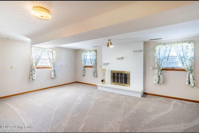 unfurnished living room featuring carpet floors, a fireplace, and baseboards